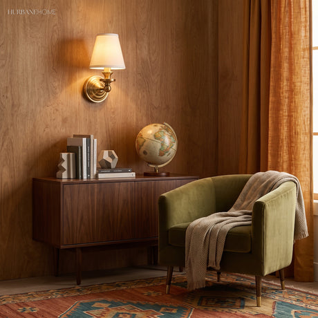 Brass sconce with linen shade lit against a deep blue wall