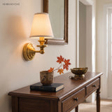 Two brass sconces flanking an arched mirror above a basin