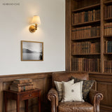 Chrome sconce with white linen shade on a plain pale wall