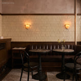Pair of frosted glass wall sconces above banquette seating in a tiled cafe
