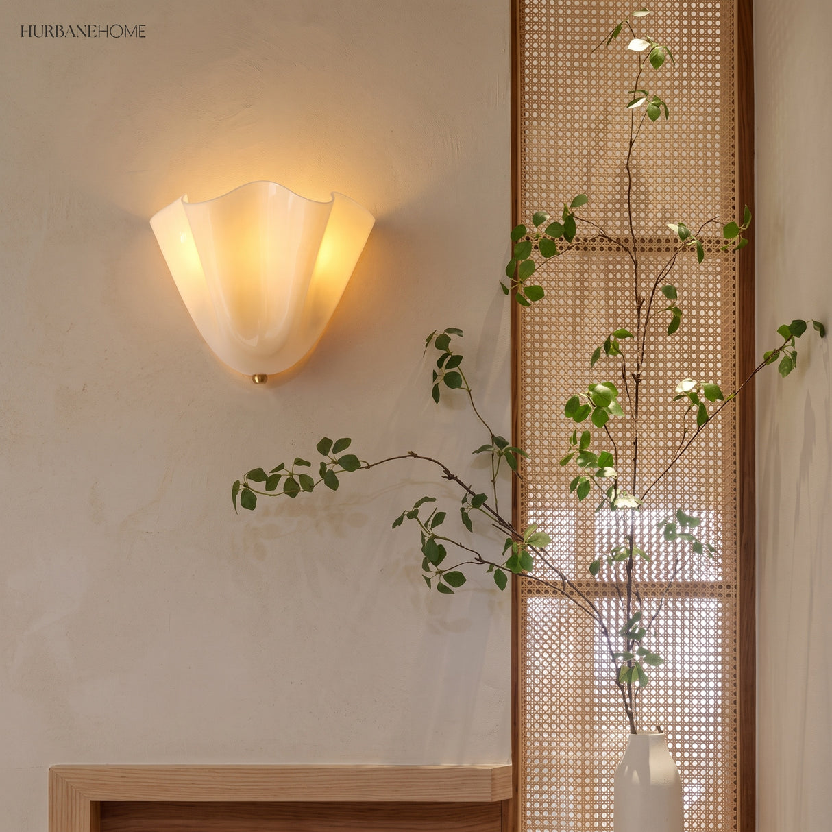 Frosted glass wall sconce beside a rattan screen and trailing plant