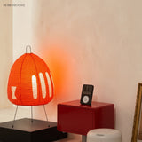 Red rice paper table lamp glowing against a warm plaster wall