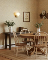 Wall sconce above a round dining table against a patterned wallpapered wall