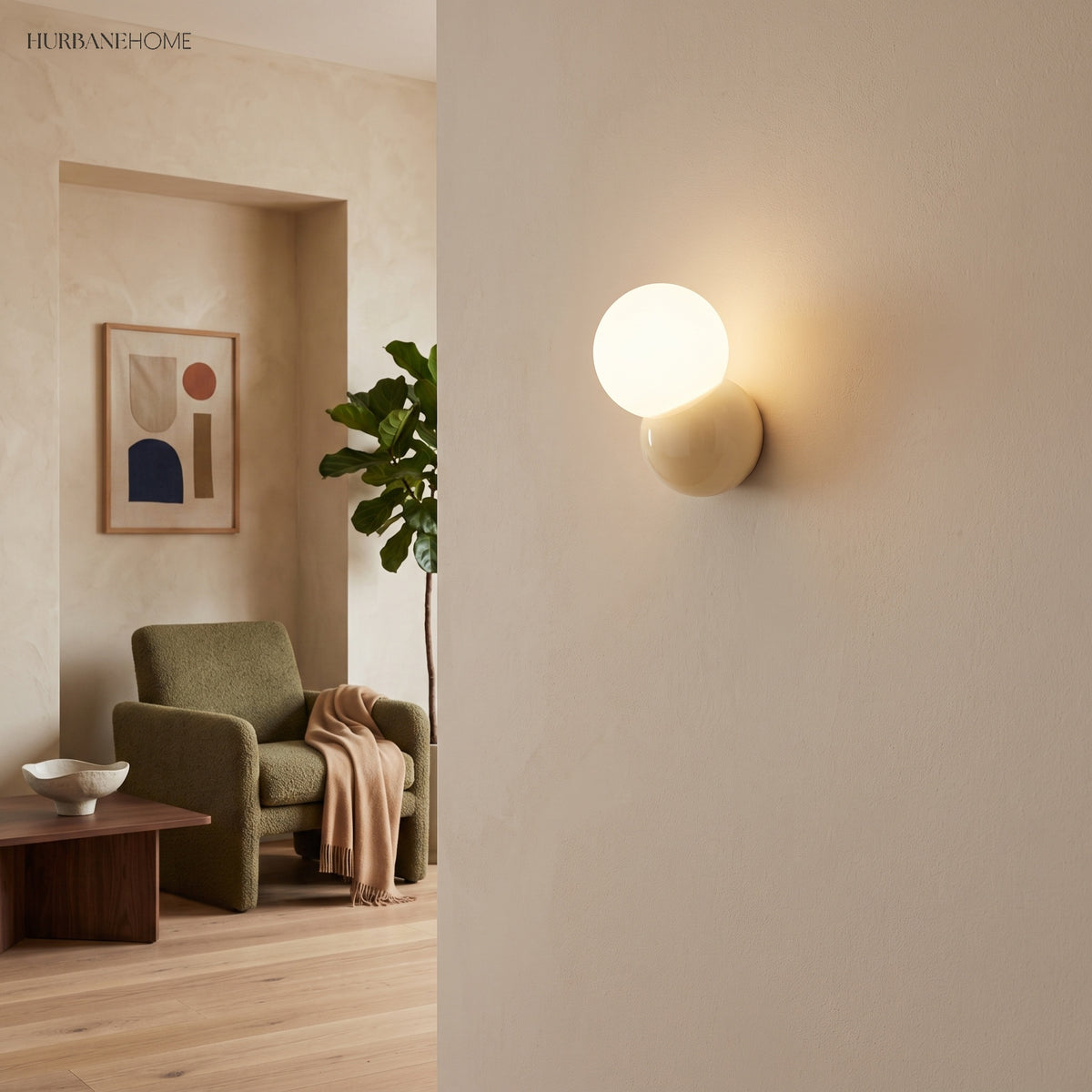Globe wall sconce on a pale plaster wall beside an opening into a green sitting room