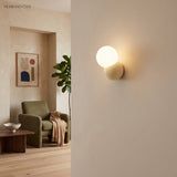 Globe wall sconce on a pale plaster wall beside an opening into a green sitting room
