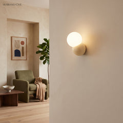 Globe wall sconce on a pale plaster wall beside an opening into a green sitting room