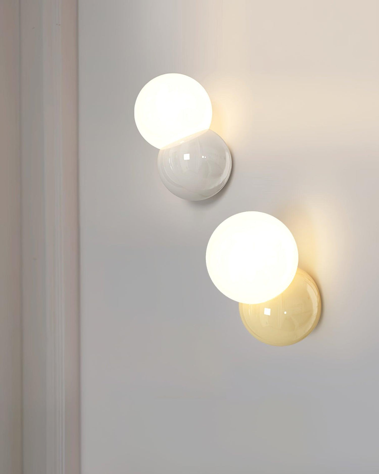 Light yellow and creamy white sconces shown together lit on a pale wall