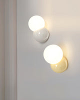 Light yellow and creamy white sconces shown together lit on a pale wall