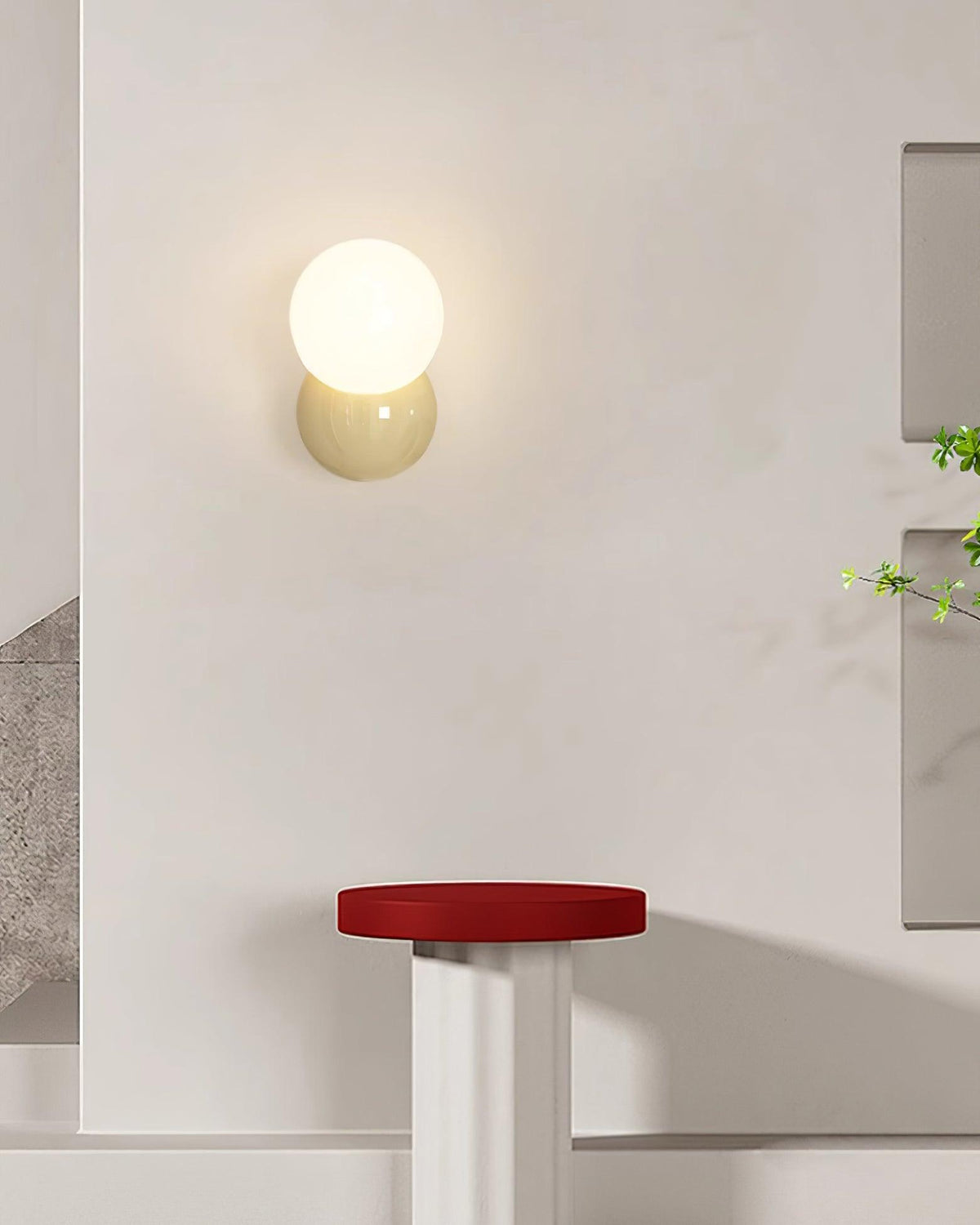 Wall sconce on a plain white wall above a small red topped stool