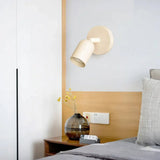 Wall sconce with the cylindrical shade tilted to one side on white background