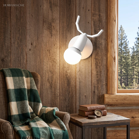 White antler sconce lit on weathered timber above a plaid armchair