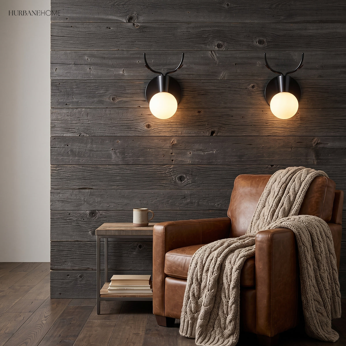 Two black antler sconces lit on a timber clad wall above an armchair