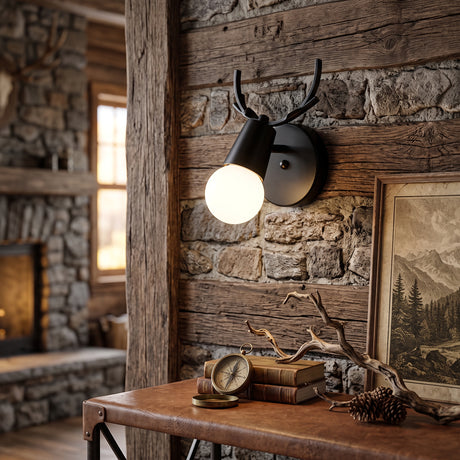 Black antler sconce lit on timber panelling beside a stone fireplace