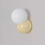 White opal globe overlapping a cream backplate, unlit against a grey wall