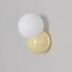 White opal globe overlapping a cream backplate, unlit against a grey wall