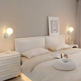 Two wall sconces mounted either side of a white bed with a framed print