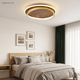 Walnut and gold round ceiling light glowing above an oak-framed bed