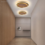 Two round walnut ceiling lights glowing along a minimalist hallway