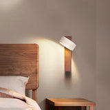 Walnut sconce with tilted stone shade above a bed and wood nightstand