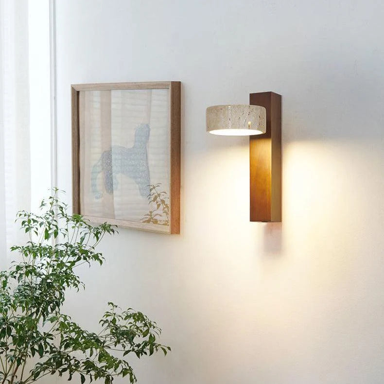 Walnut sconce with tilted stone shade near a framed picture and green plant