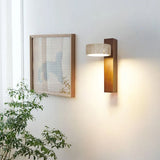 Walnut sconce with tilted stone shade near a framed picture and green plant