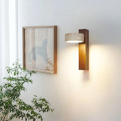Walnut sconce with tilted stone shade near a framed picture and green plant