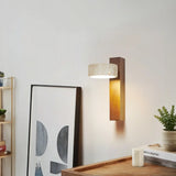 Walnut travertine sconce on a wall by open shelving, framed art and a plant