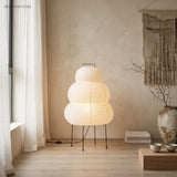 Lit rice paper floor lamp by a curtained window with a ceramic vase
