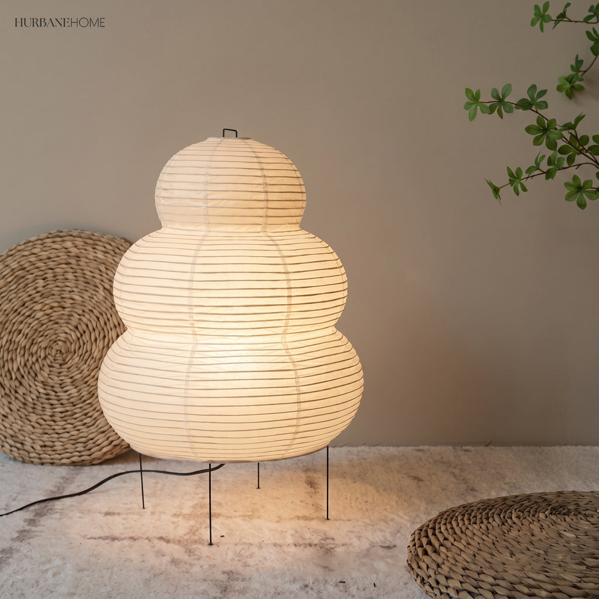 Rice paper floor lamp glowing beside woven floor cushions