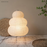 Rice paper floor lamp glowing beside woven floor cushions