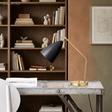 White shade brass table lamp on a wood desk in a library