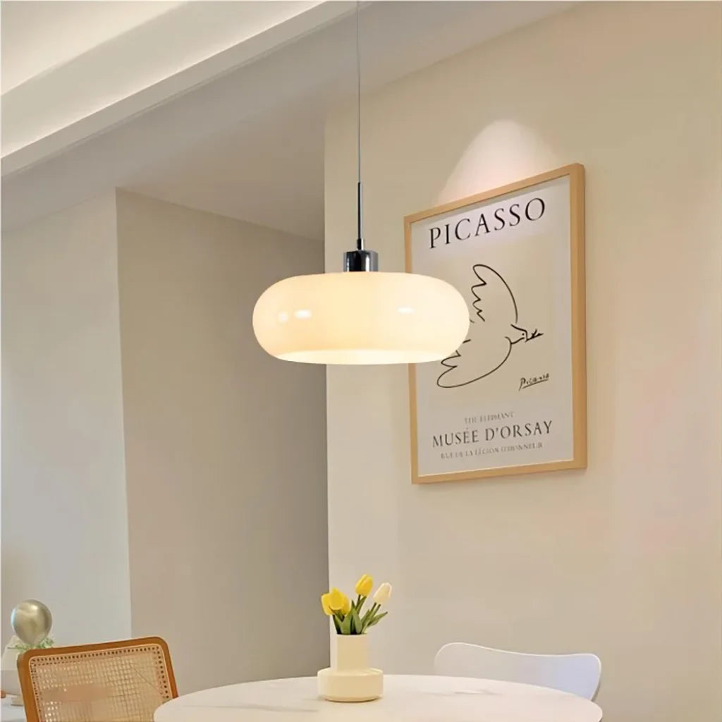 White glass pendant light glowing beside an arched doorway in a dining space