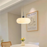 White glass pendant light glowing beside an arched doorway in a dining space