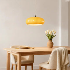 White glass pendant light above a dining table near a framed line-art poster