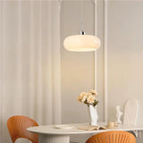 White glass pendant light over a glass side table beside seascape wall art