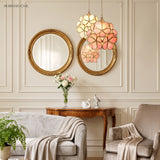White and pink floral pendant lights beside a gilt mirror in an elegant lounge