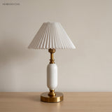 White pleated shade lamp with glossy white column and brass base