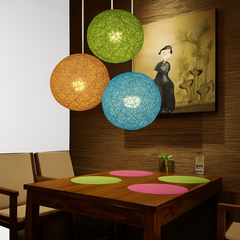 Three woven globes lit above a dining table and artwork
