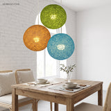 Green, orange and blue woven globe pendants above a dining table