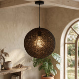 Dark woven globe pendant lit above a console in an arched room