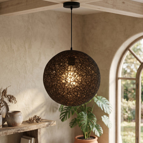 Dark woven globe pendant lit above a console in an arched room