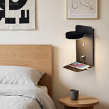 Black wall lamp with round LED head charging a phone in a bedroom
