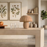 Rattan table lamp on a wood bench beside a boucle armchair and jute rug