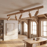 Natural wood track light with five heads lit across a beamed timber ceiling