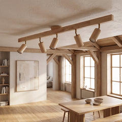 Natural wood track light with five heads lit across a beamed timber ceiling