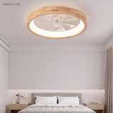 Wood ceiling fan light glowing warmly above a grey upholstered bed