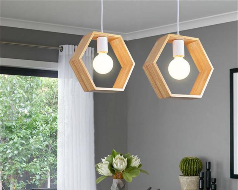 Two wood frame pendants hanging by a window with plants below