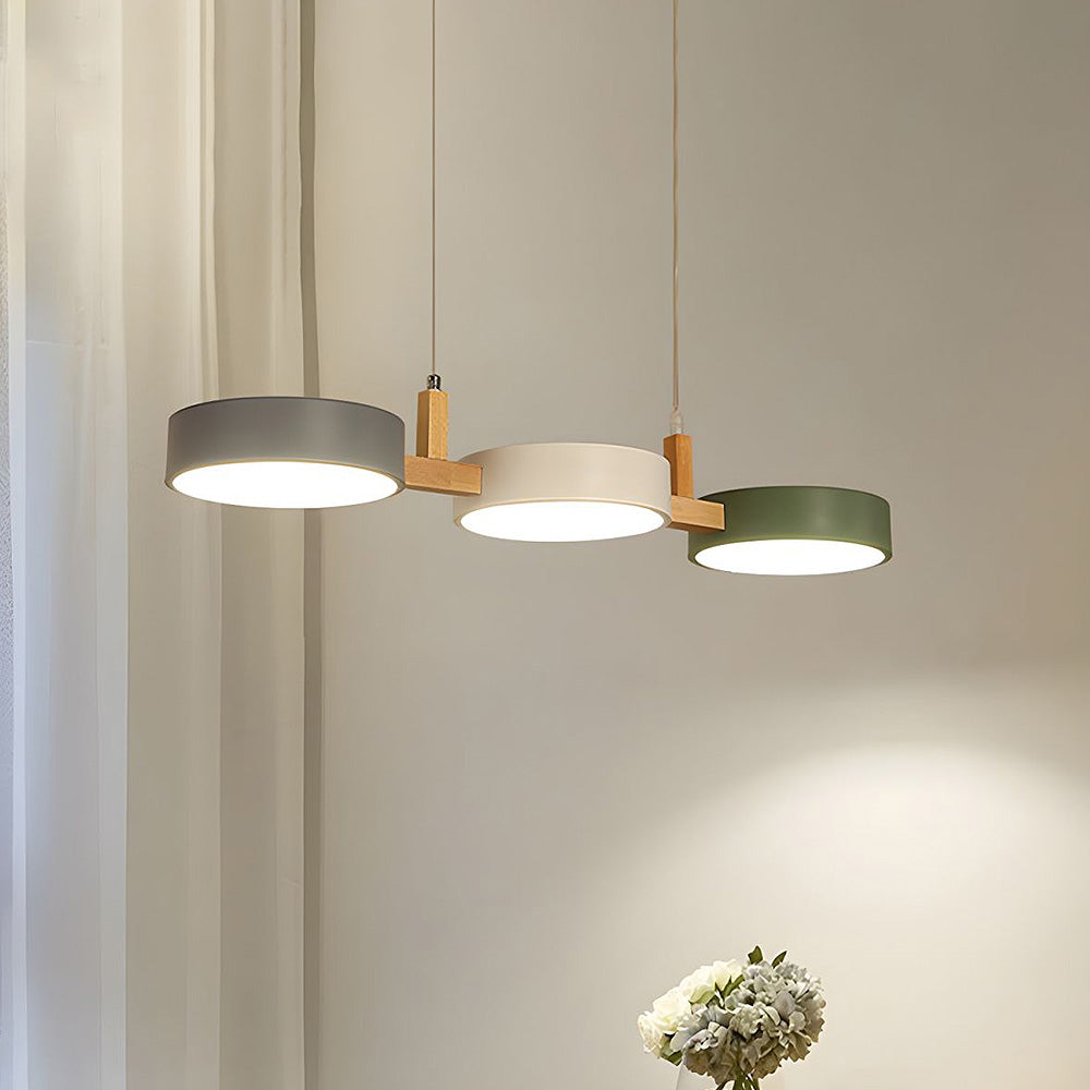 Staggered drum shades in grey, cream and green hanging from thin white cables