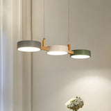 Staggered drum shades in grey, cream and green hanging from thin white cables