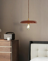 Wood pendant hanging beside a bedside cabinet with a radio and a cream headboard
